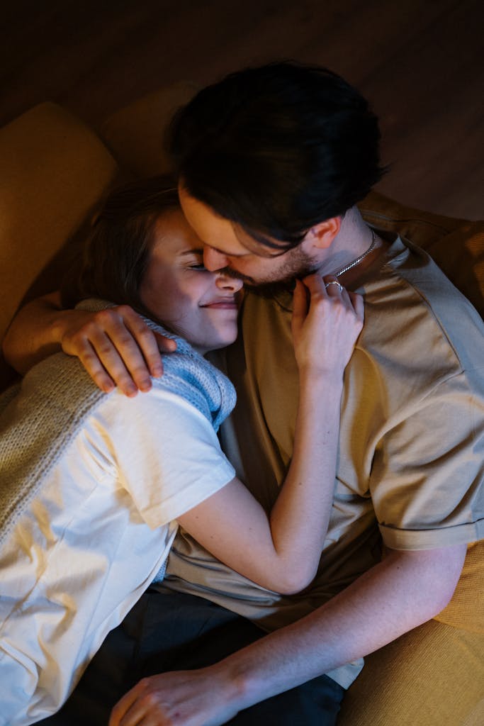 A couple lovingly embracing on a cozy sofa at night, creating a warm and intimate atmosphere.