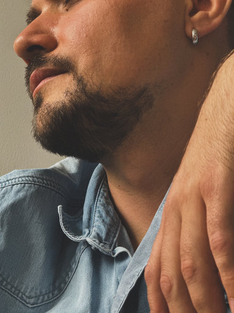 A side profile of a man wearing a denim shirt, showcasing a casual and rugged style.