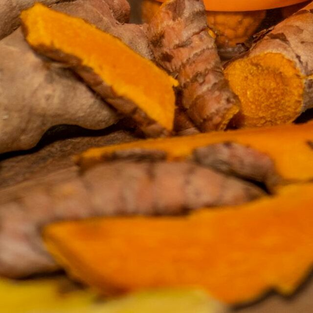 Close-up of turmeric and ginger supplement bottle on a kitchen counter.