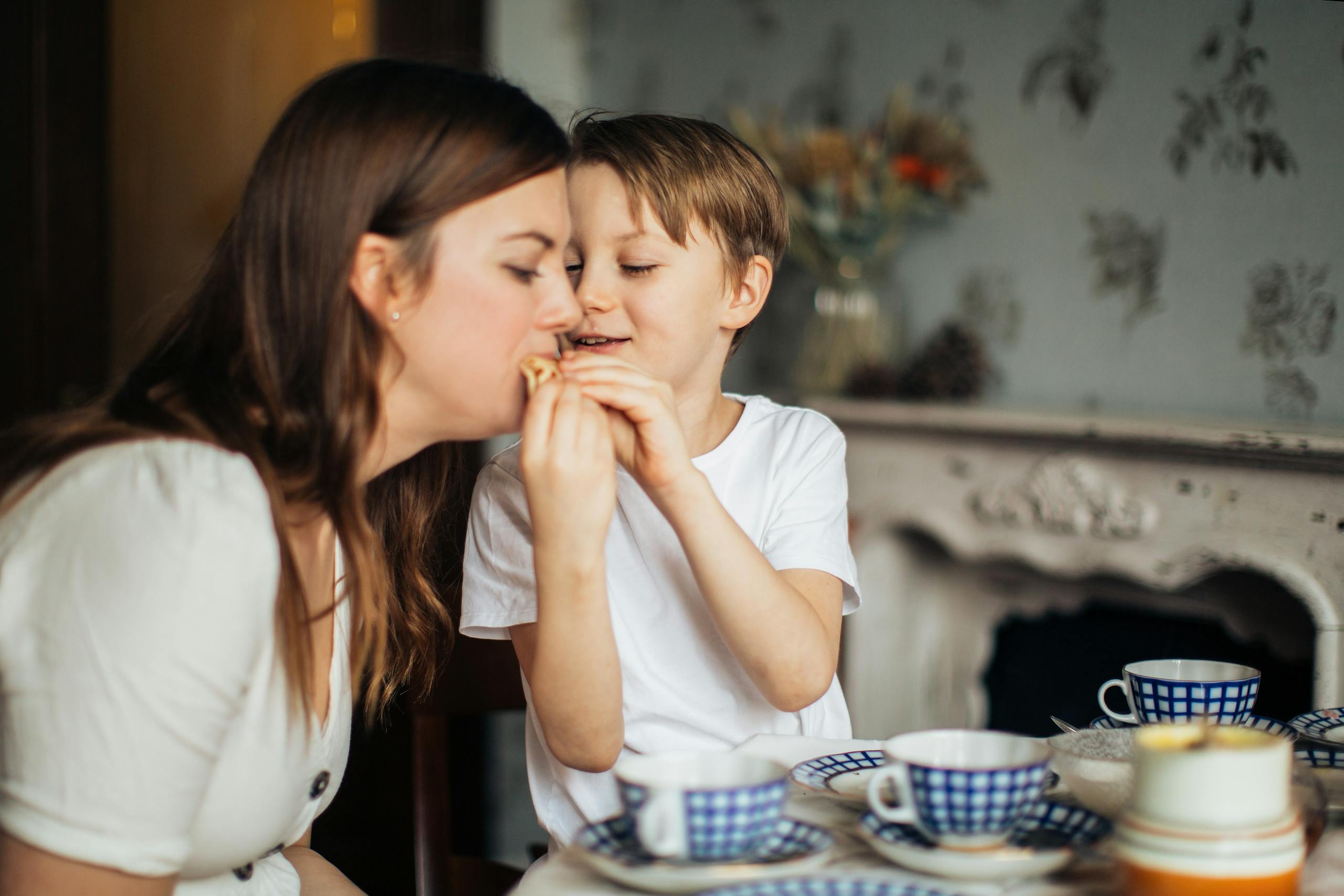 Cozy moment of mother and son enjoying snacks together at a table.